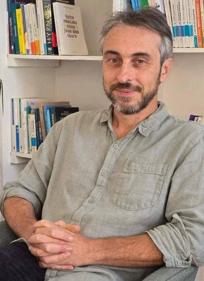 Baptiste Martin, hypnothérapeute, devant sa bibliothèque